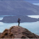 a person standing on a hill with a body of water in the background